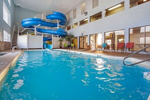 Ein Hallenbad mit mehreren Wasserrutschen und einem Sitzbereich mit Stühlen und Tischen.