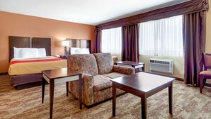 A hotel room with a bed, a sofa, a table, and a desk.