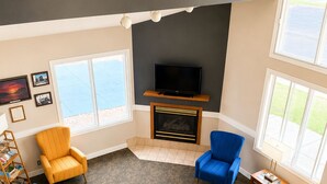 A living room with a fireplace, a television, and two windows. - Days Inn by Wyndham Hinckley (Hinckley)