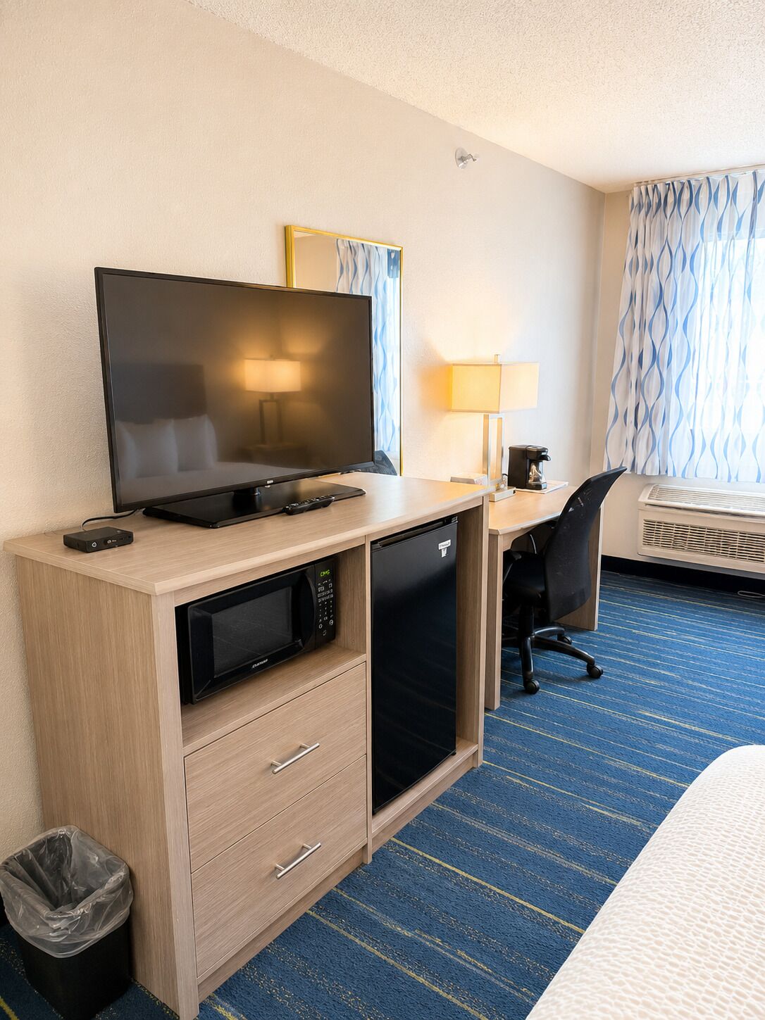 A hotel room with a television, desk, chair, and a bed.