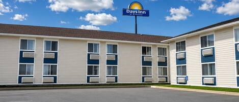 Un motel Days Inn avec un parking et un ciel bleu dégagé parsemé de nuages.