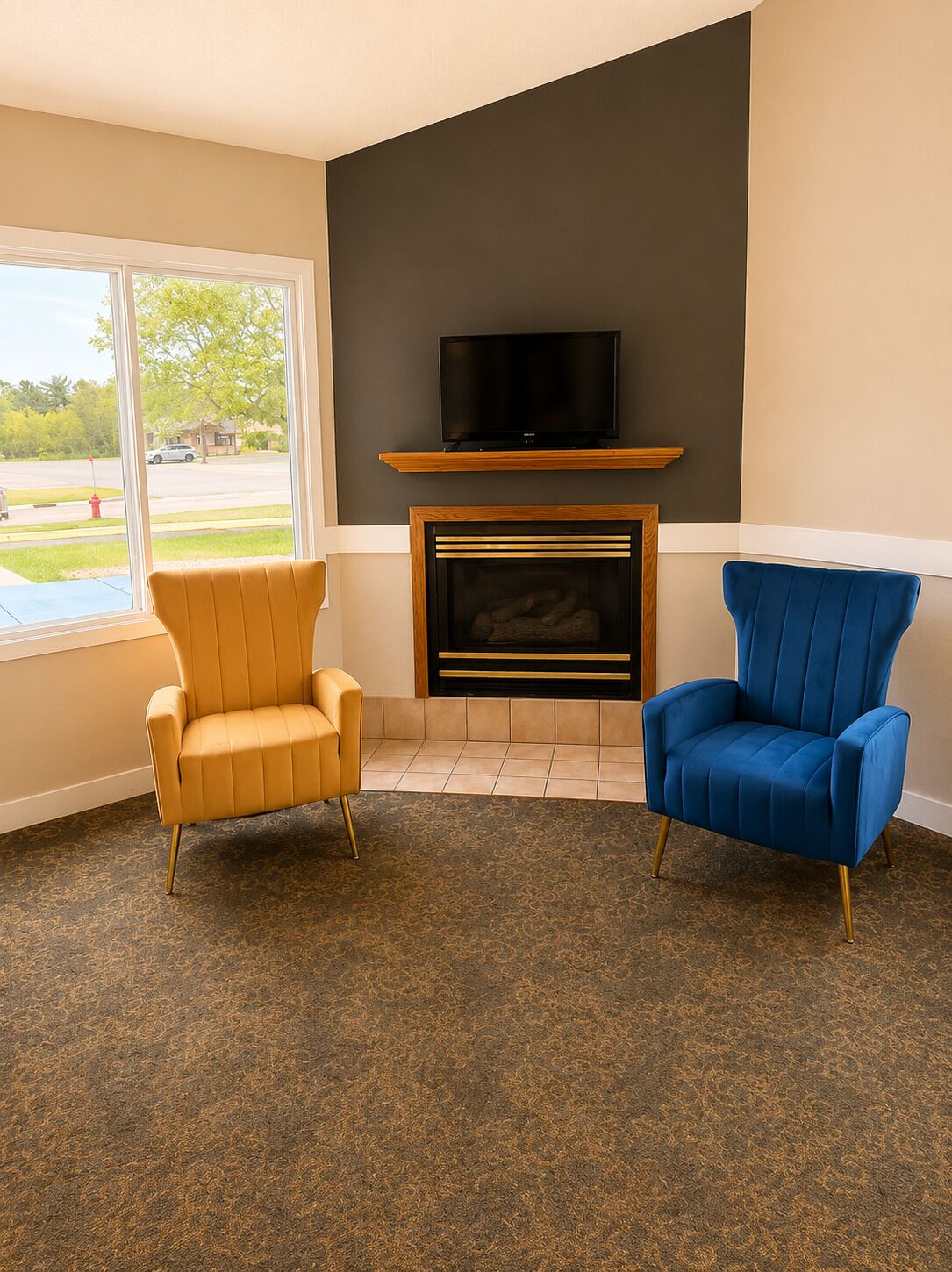 Una sala de estar con dos sillones, chimenea, televisor y vistas al exterior.