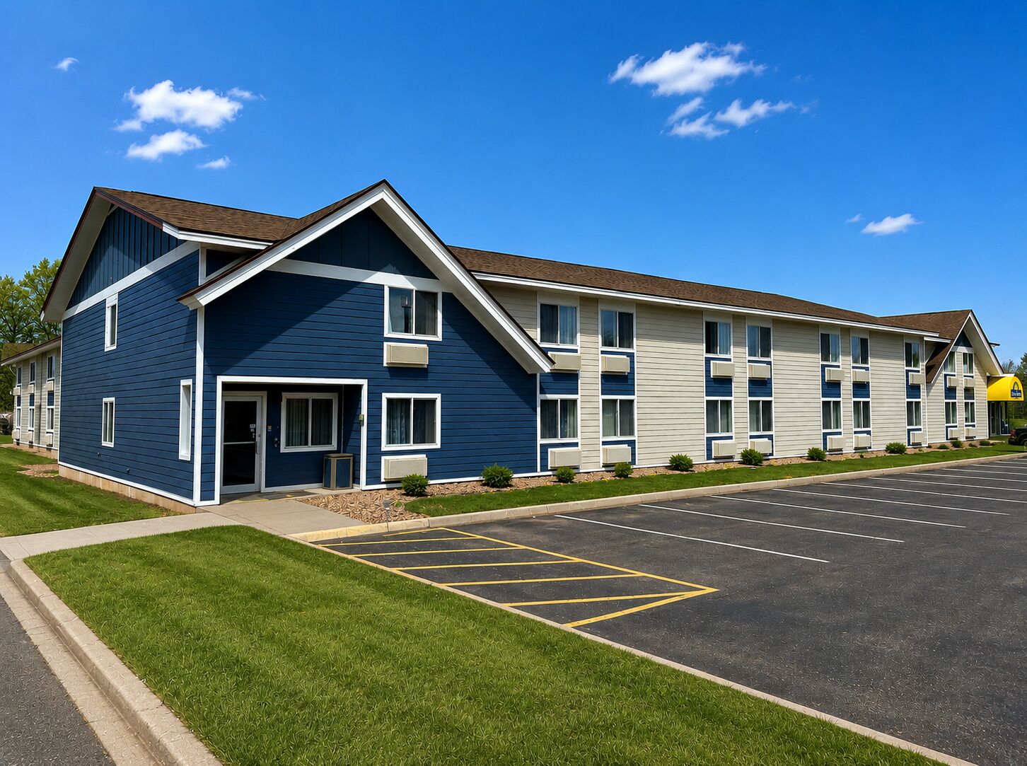 A two-story hotel with a blue exterior, a parking lot, and a McDonald's sign.