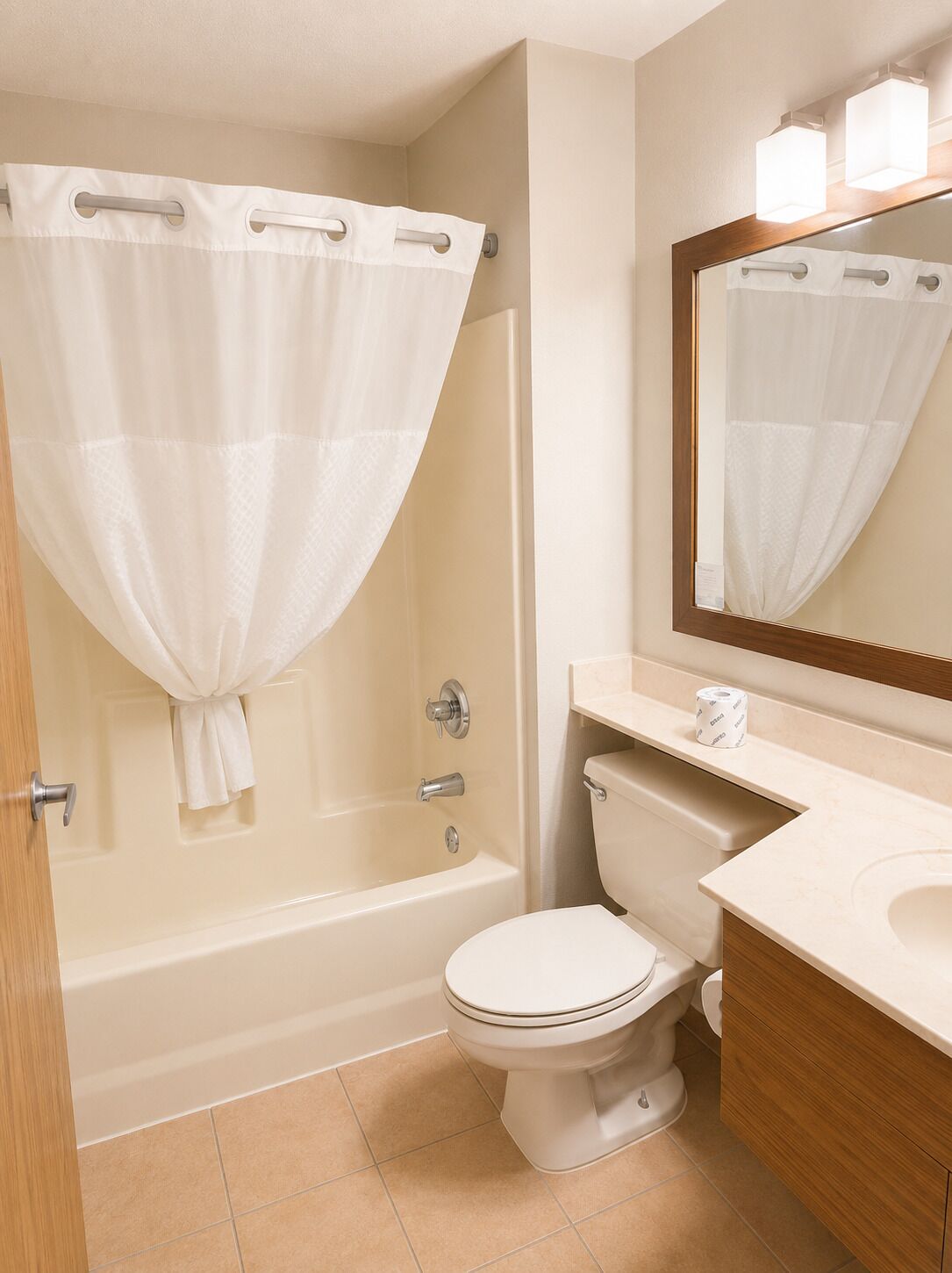 A bathroom with a bathtub, toilet, and a mirror.
