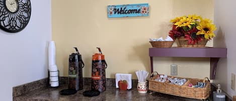 A reception area with a coffee station, a welcome sign, and a basket of flowers.