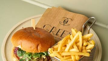 Un sándwich con papas fritas en un plato, una servilleta de madera con un logotipo y un tenedor de metal.
