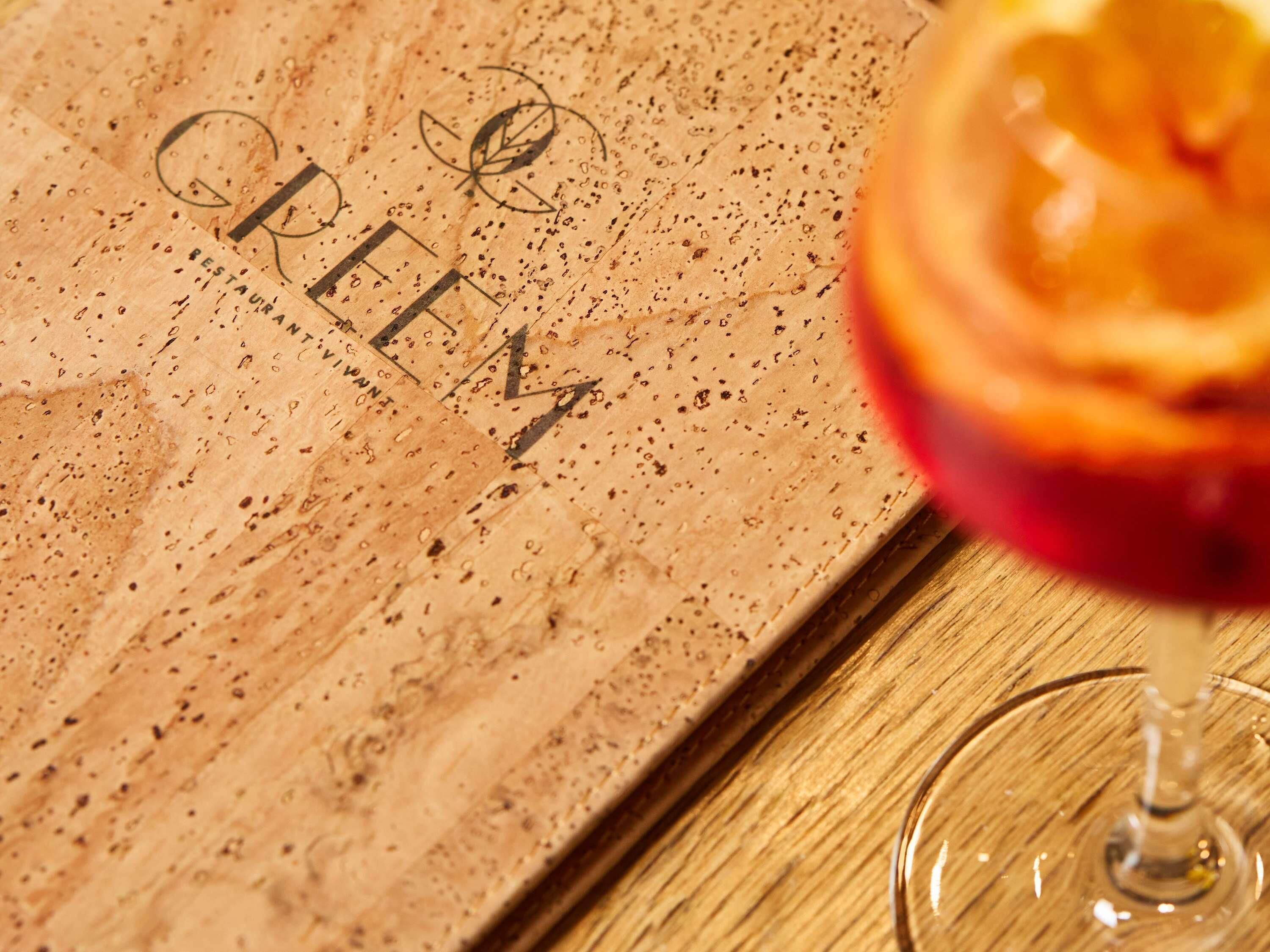 A cork coaster with the word 'REEM' and a glass with a fruit garnish.