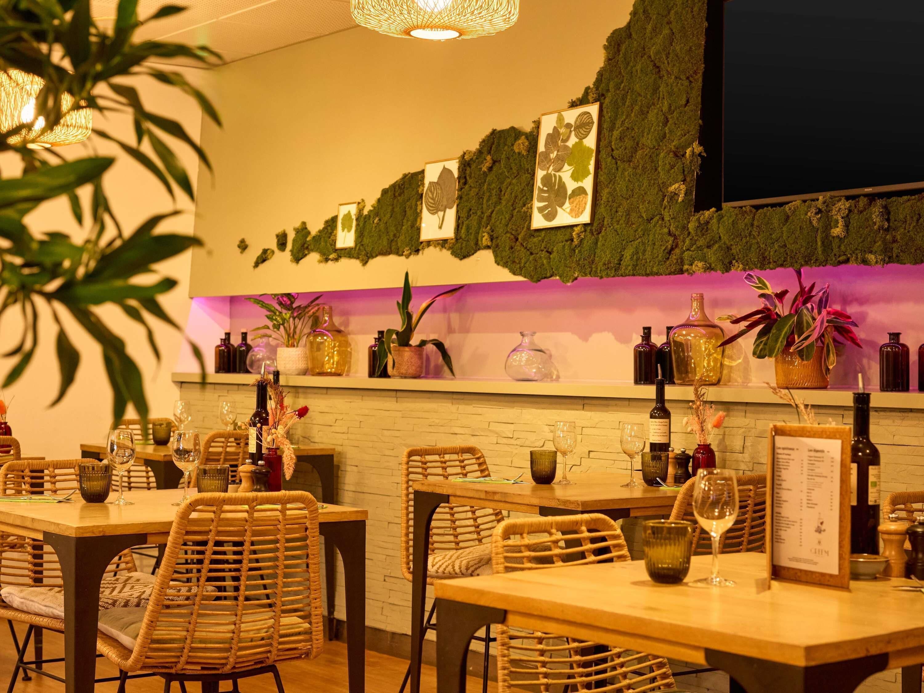 Interior de restaurante com mesas, cadeiras, garrafas de vinho e um quadro de ementa.
