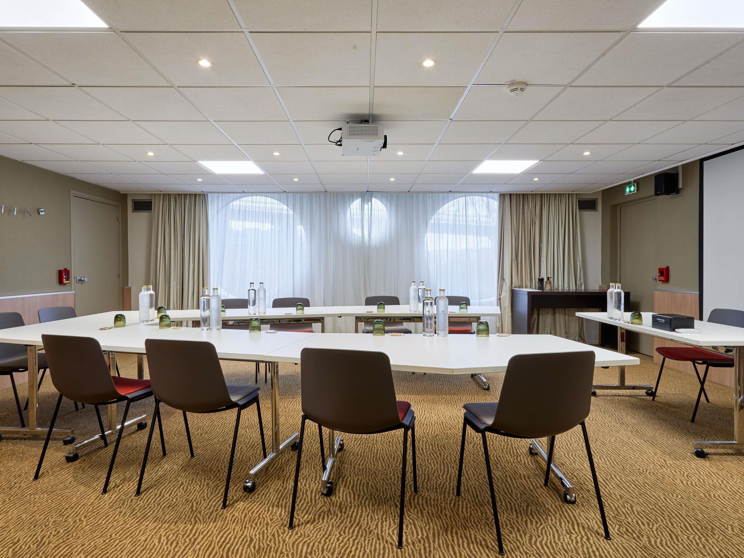 Een vergaderruimte met een lange tafel, stoelen en een projector.