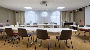 A conference room with a long table, chairs, and a projector. - Novotel Paris La Défense Esplanade (Courbevoie)