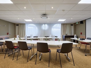 A conference room with a long table, chairs, and a projector. - Novotel Paris La Défense Esplanade (Courbevoie)