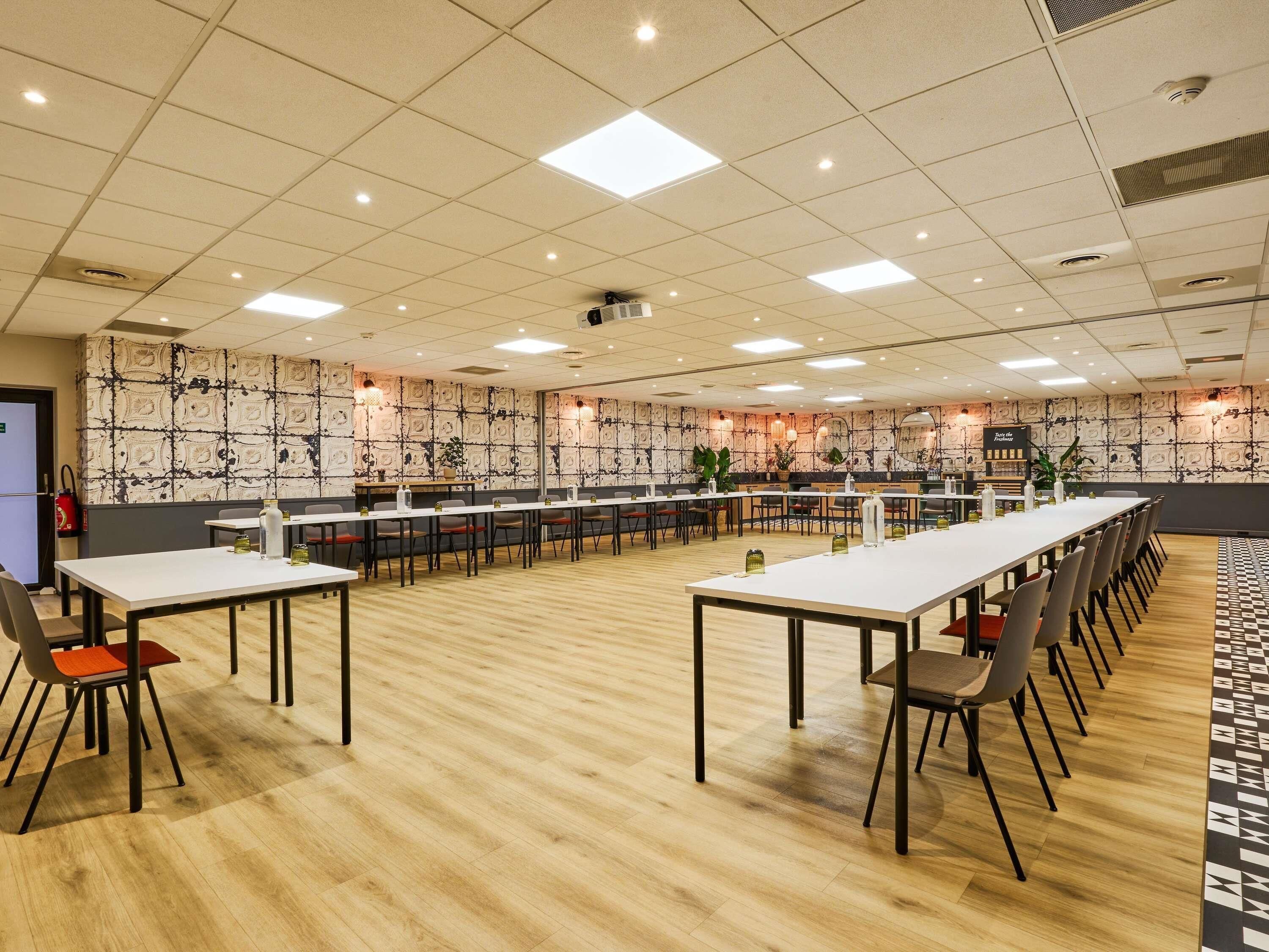 Un salón de conferencias con mesas largas, sillas y un papel tapiz estampado.