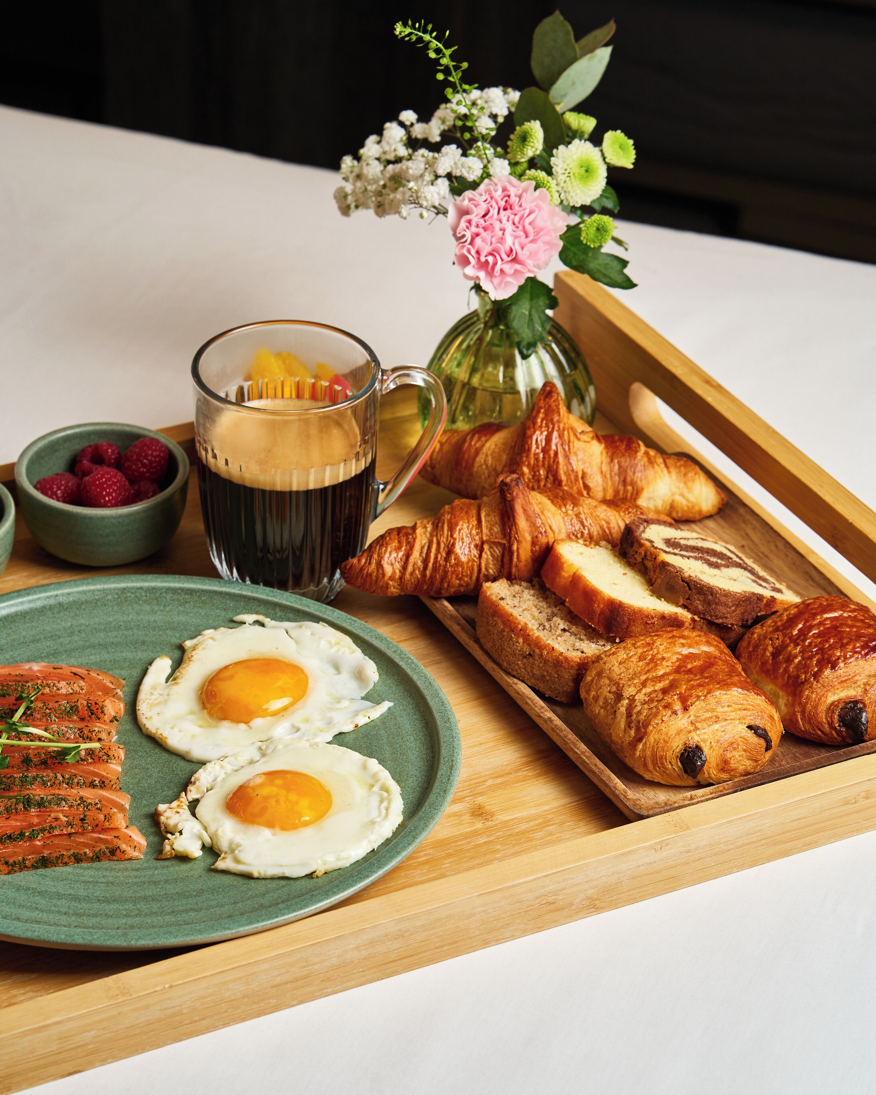 Un plateau de petit-déjeuner avec des croissants, des œufs, du saumon fum é et une tasse de café.