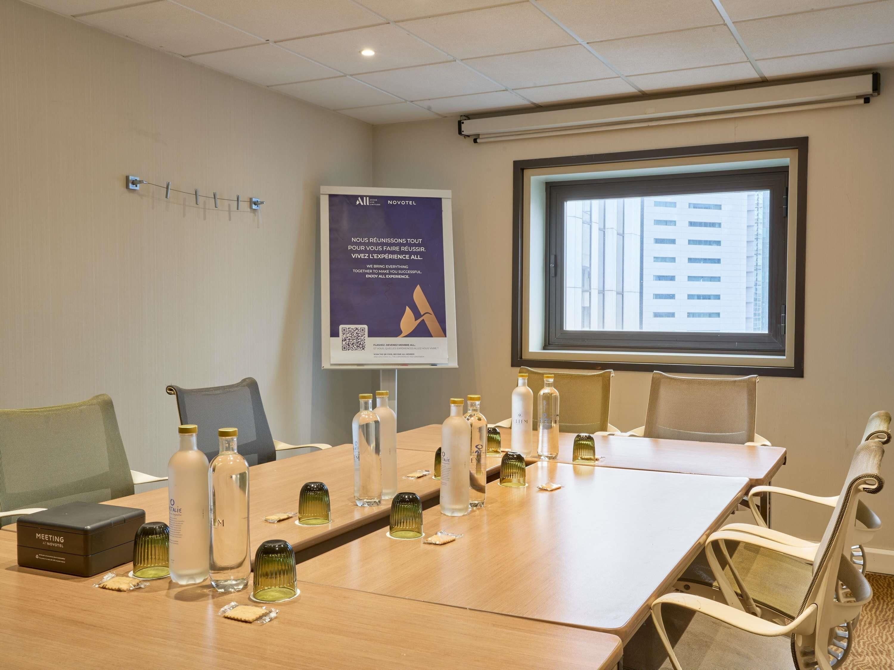 A meeting room with a long table, chairs, a projector screen, and a banner on the wall.