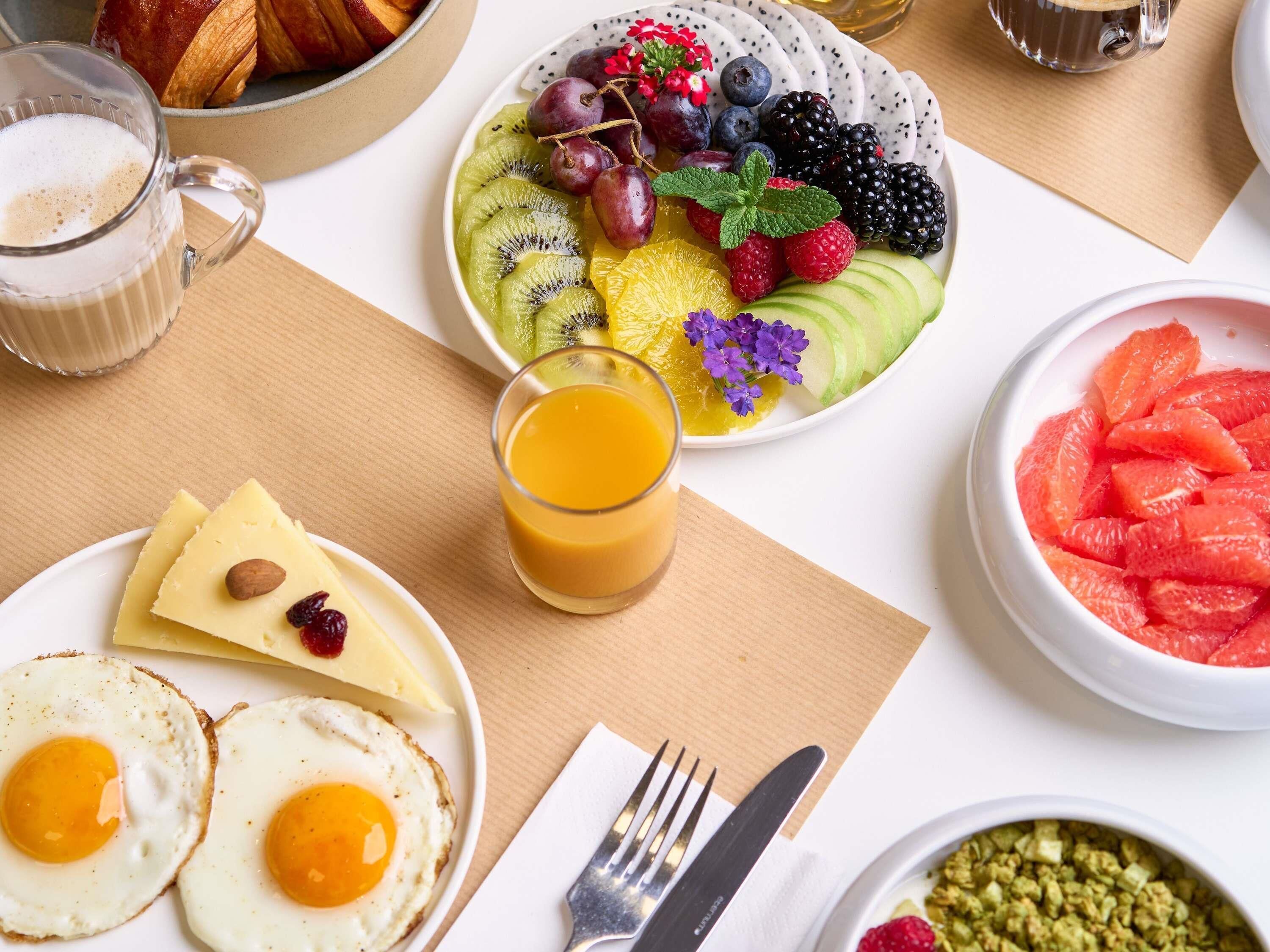 Un petit-déjeuner composé d’œufs, de pain grillé, de fruits et de jus de fruits.