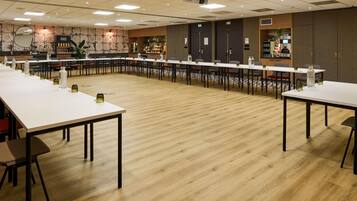 A conference room with long tables, chairs, and a projector screen.