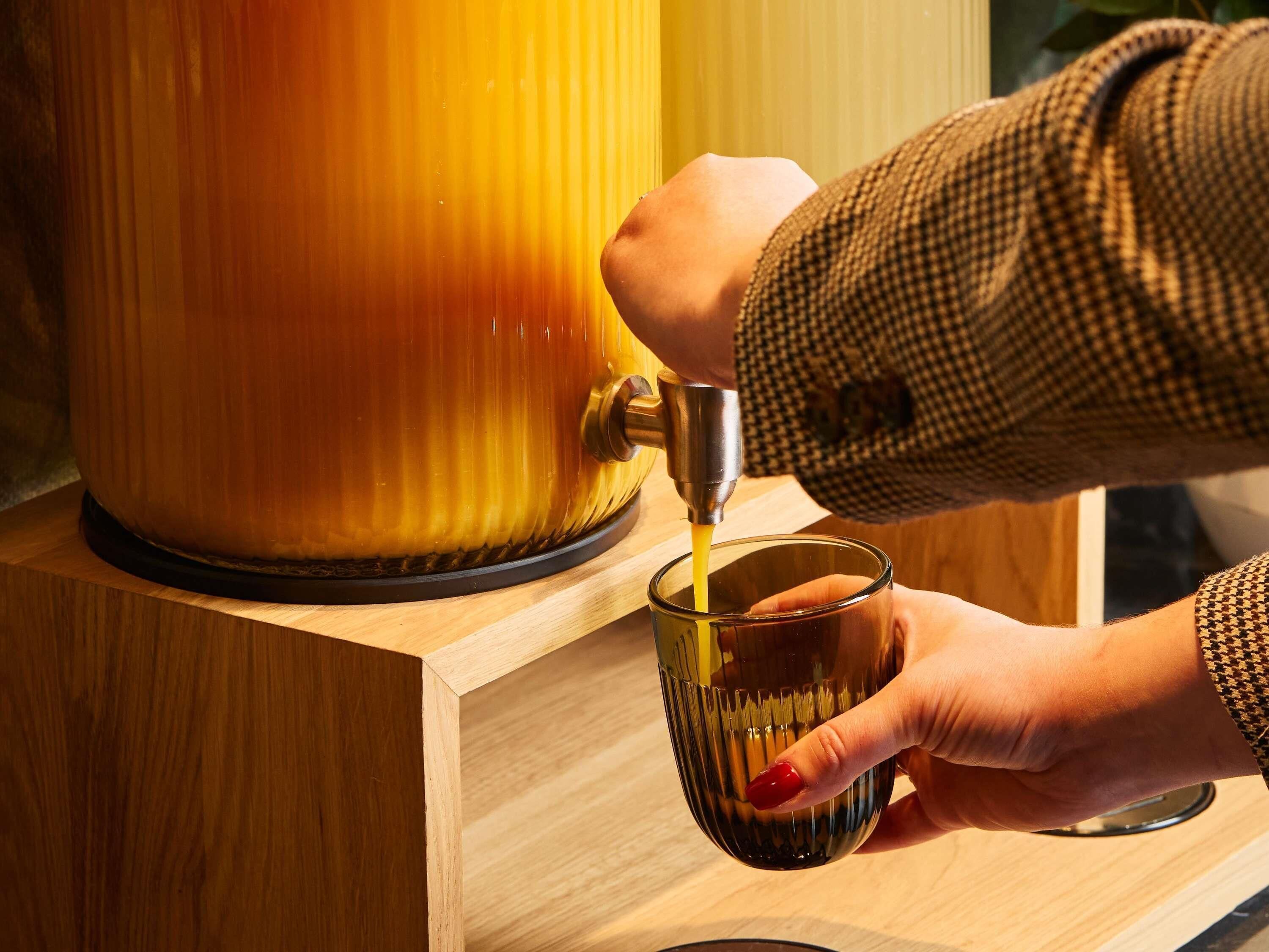 A hand pouring a beverage from a tap into a glass.