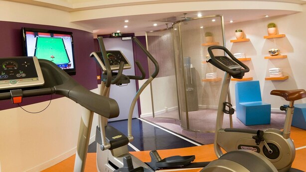 A gym with cardio machines, a treadmill, and a stationary bike. - Novotel Paris La Défense Esplanade (Courbevoie)