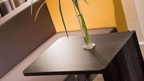 A modern, dark wooden table with a clear glass vase containing a green plant. - Novotel Paris La Défense Esplanade (Courbevoie)