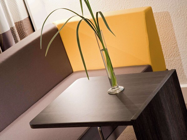 A modern, dark wooden table with a clear glass vase containing a green plant. - Novotel Paris La Défense Esplanade (Courbevoie)