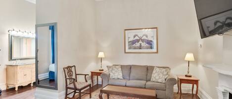 A living room with a sofa, two chairs, a coffee table, a fireplace, a TV, and a chandelier.