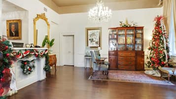 A spacious living room with a fireplace, a chandelier, and a Christmas tree.