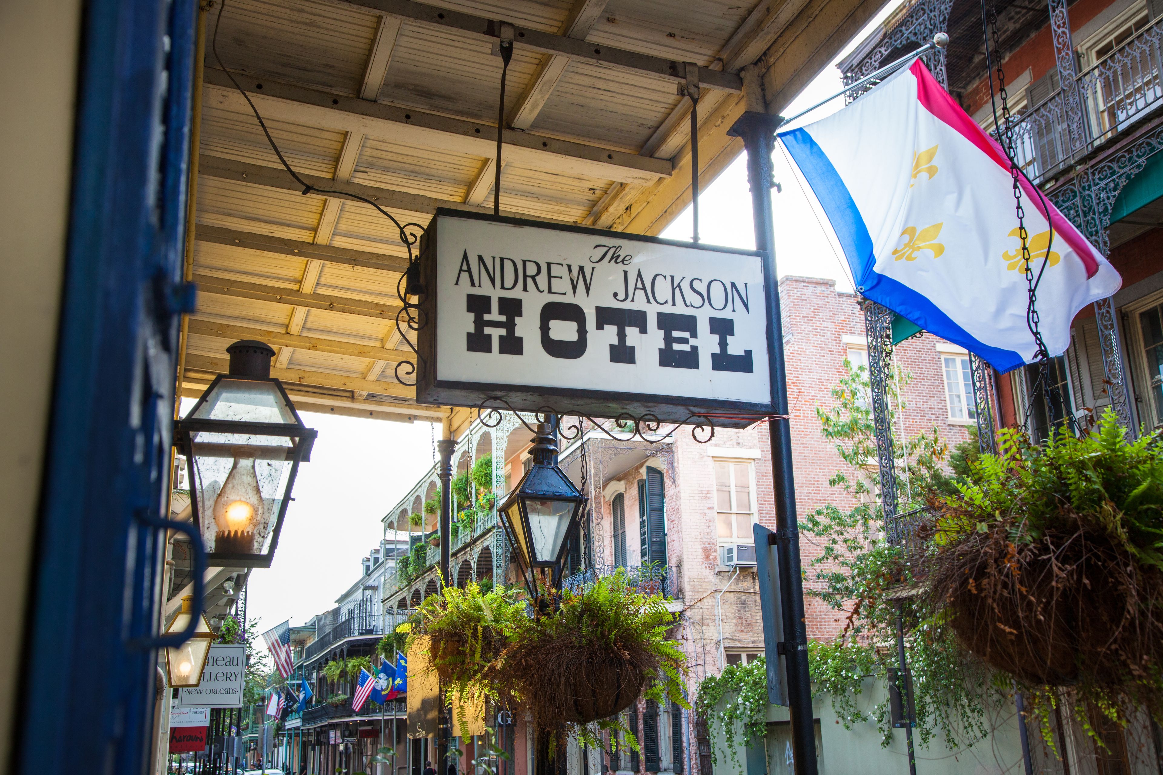 A hotel sign for "The Andrew Jackson Hotel" with hanging plants and a flag.