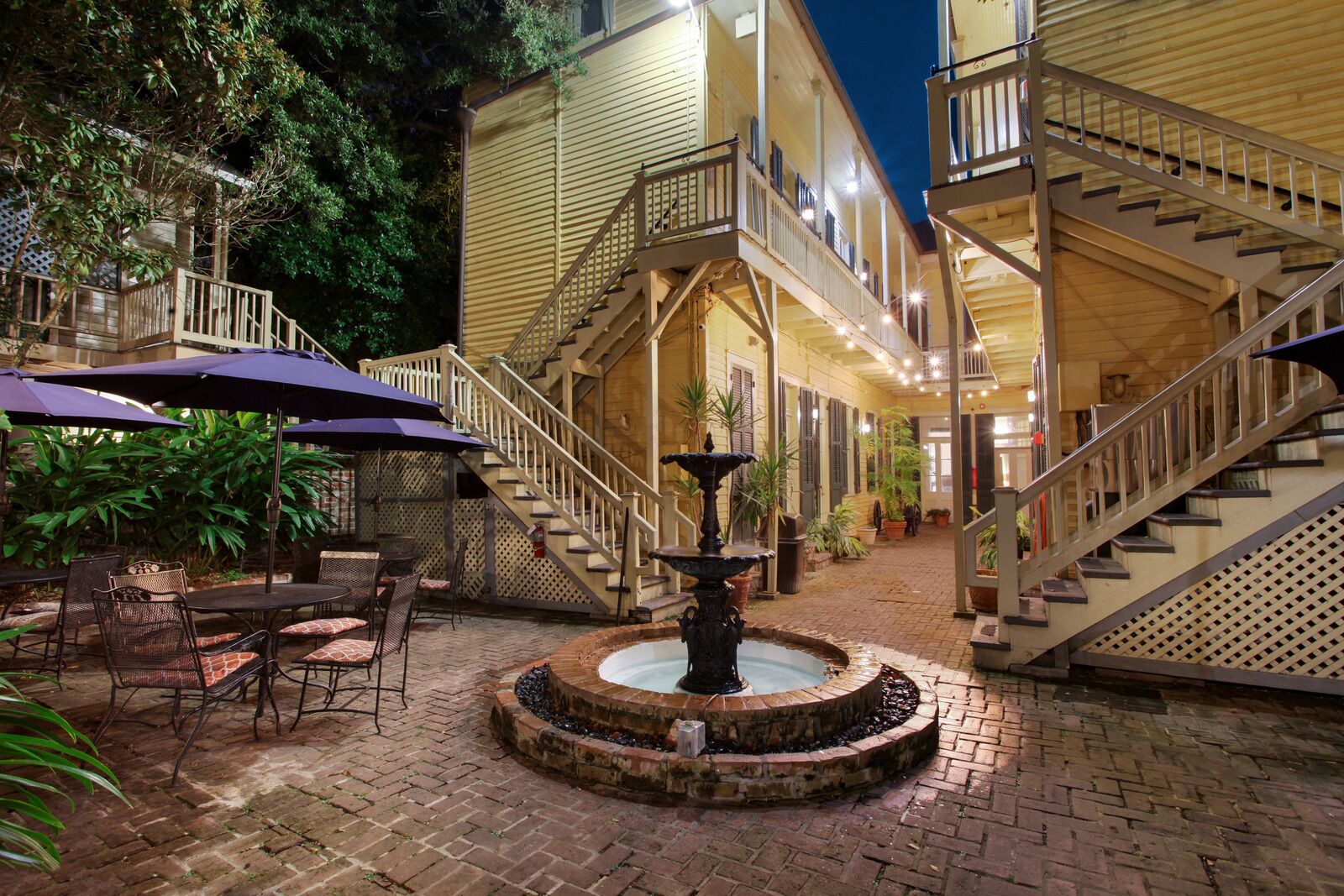 A courtyard with outdoor seating, a fountain, and a staircase leading to an upper level.