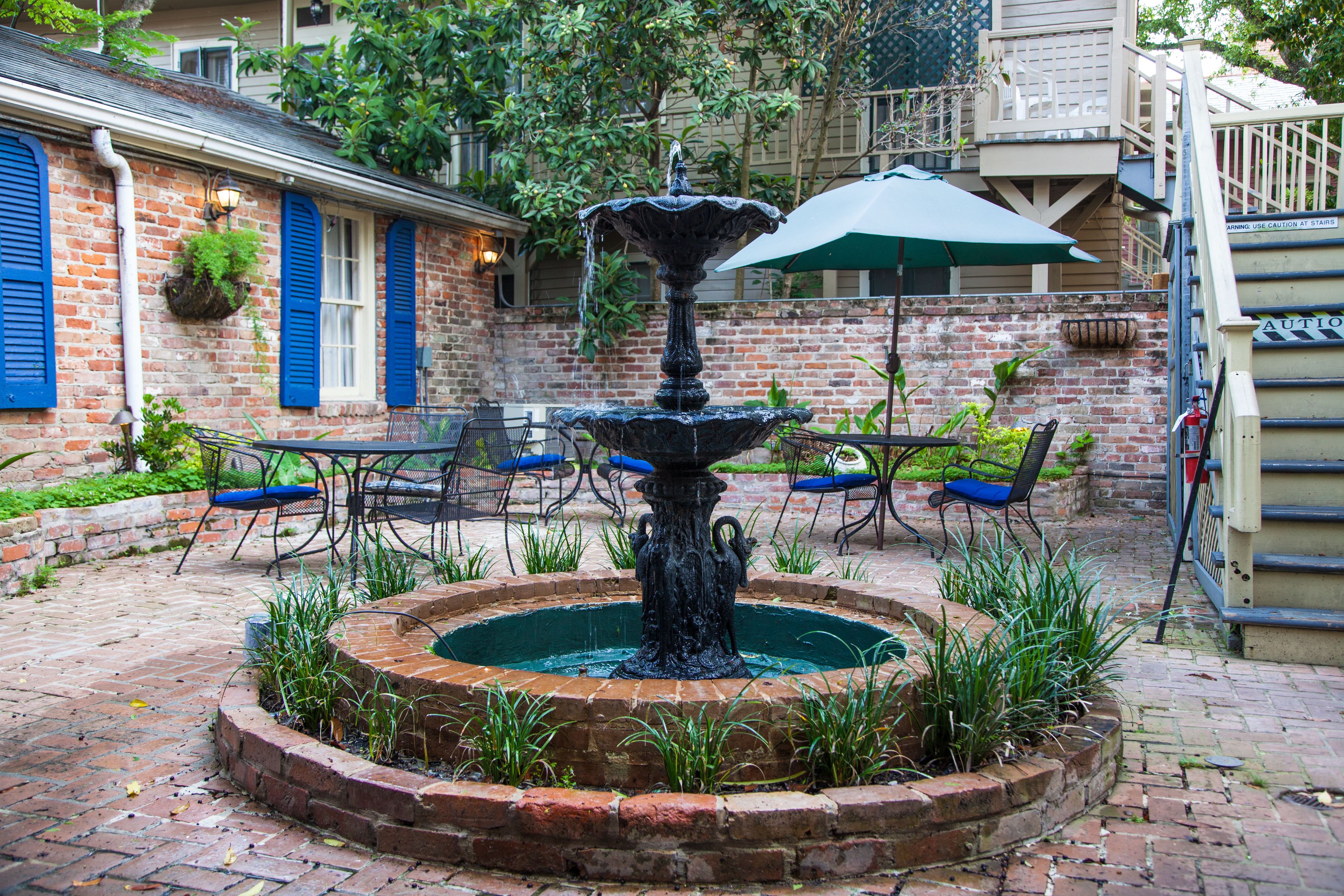 Une cour intérieure avec une fontaine centrale, des murs en briques et des espaces de repos en plein air.