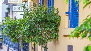 Un bâtiment avec des volets bleus, une lanterne allumée et une enseigne sur laquelle on peut lire « HÔTEL ».
