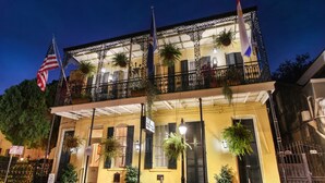 Un bâtiment à deux étages doté d’un balcon, de plantes en pot et de drapeaux.