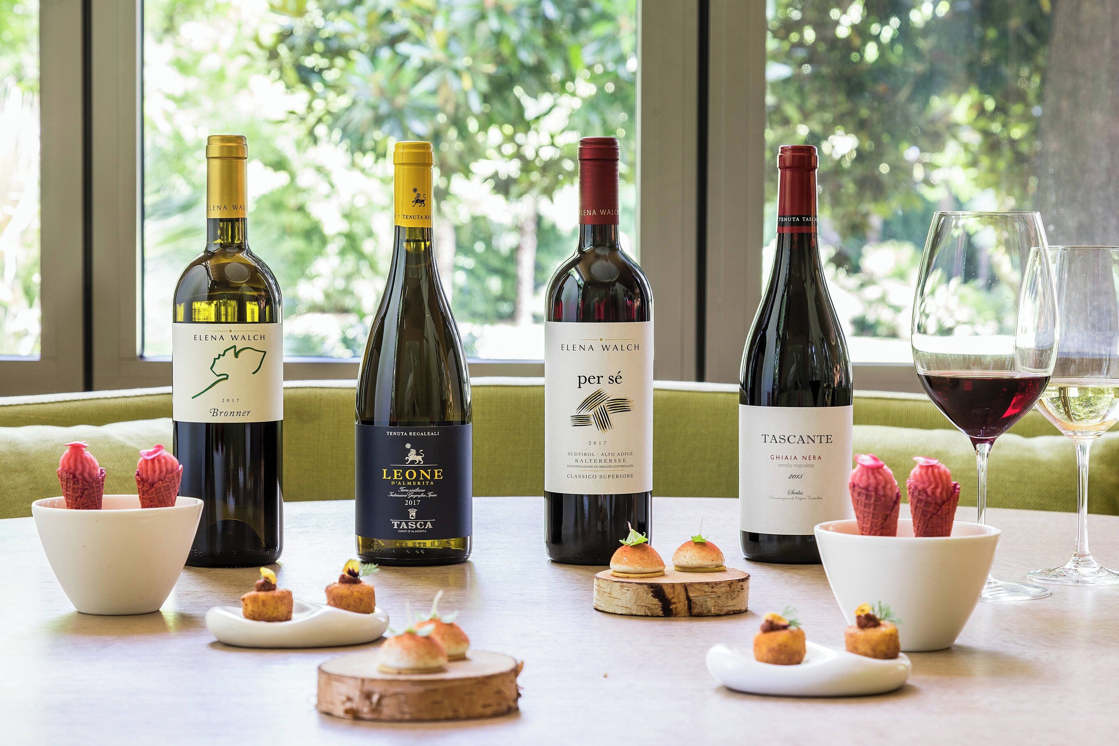A table with wine bottles, glasses, and food items.