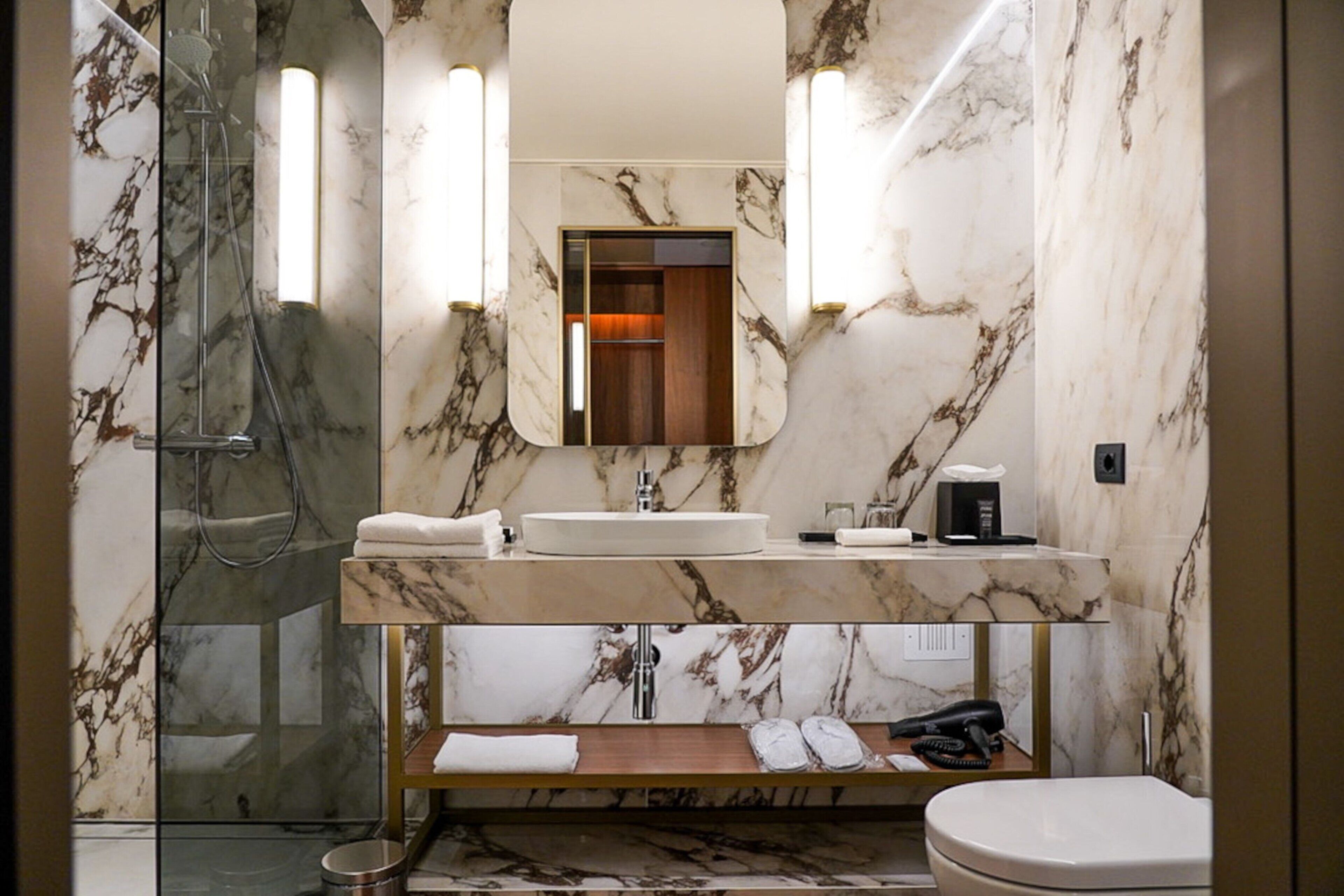 Un baño moderno con tocador de mármol, cabina de ducha de vidrio y un inodoro.