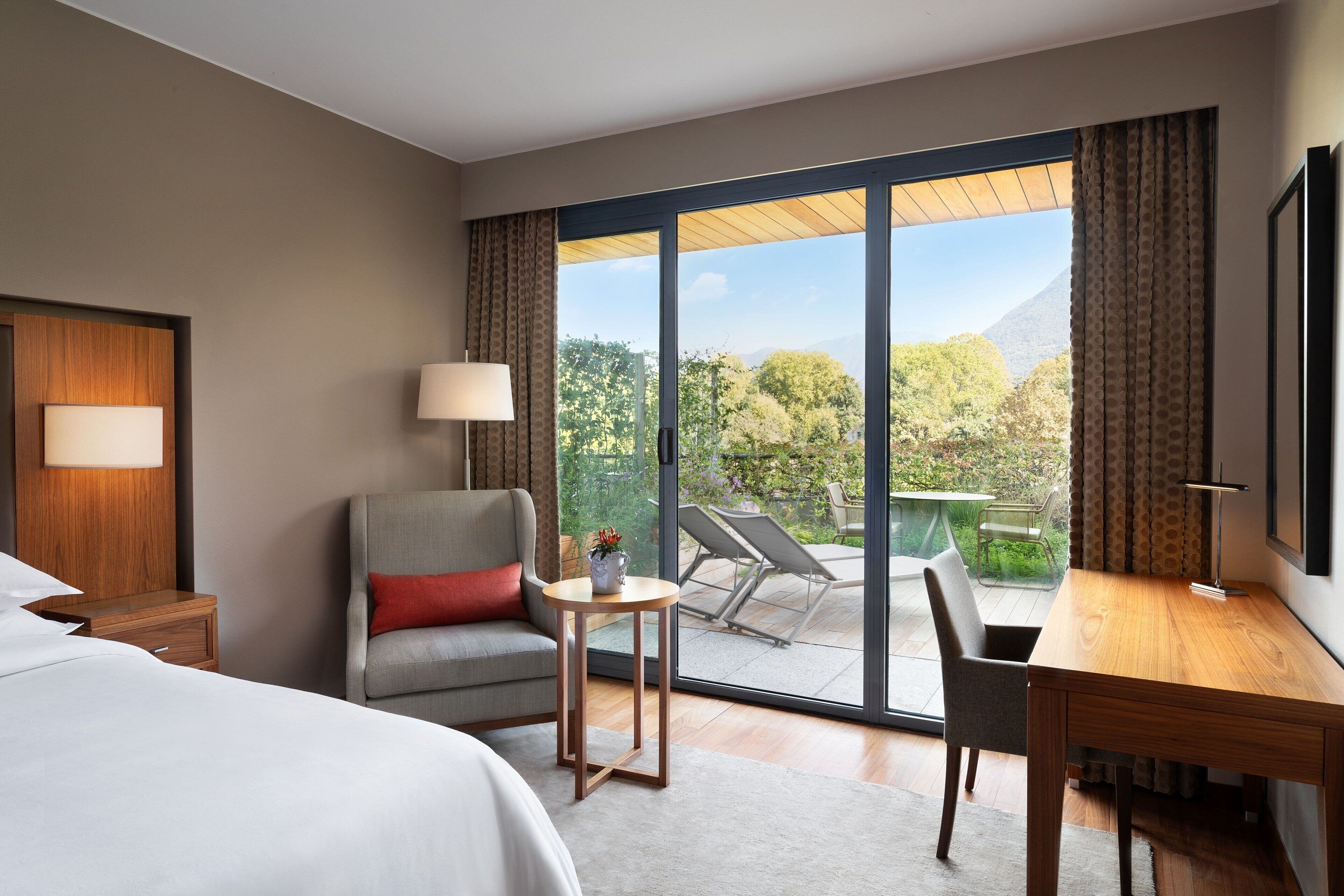 Une chambre d’hôtel comprenant un lit, un bureau, une chaise, une petite table et une vue sur l’extérieur.