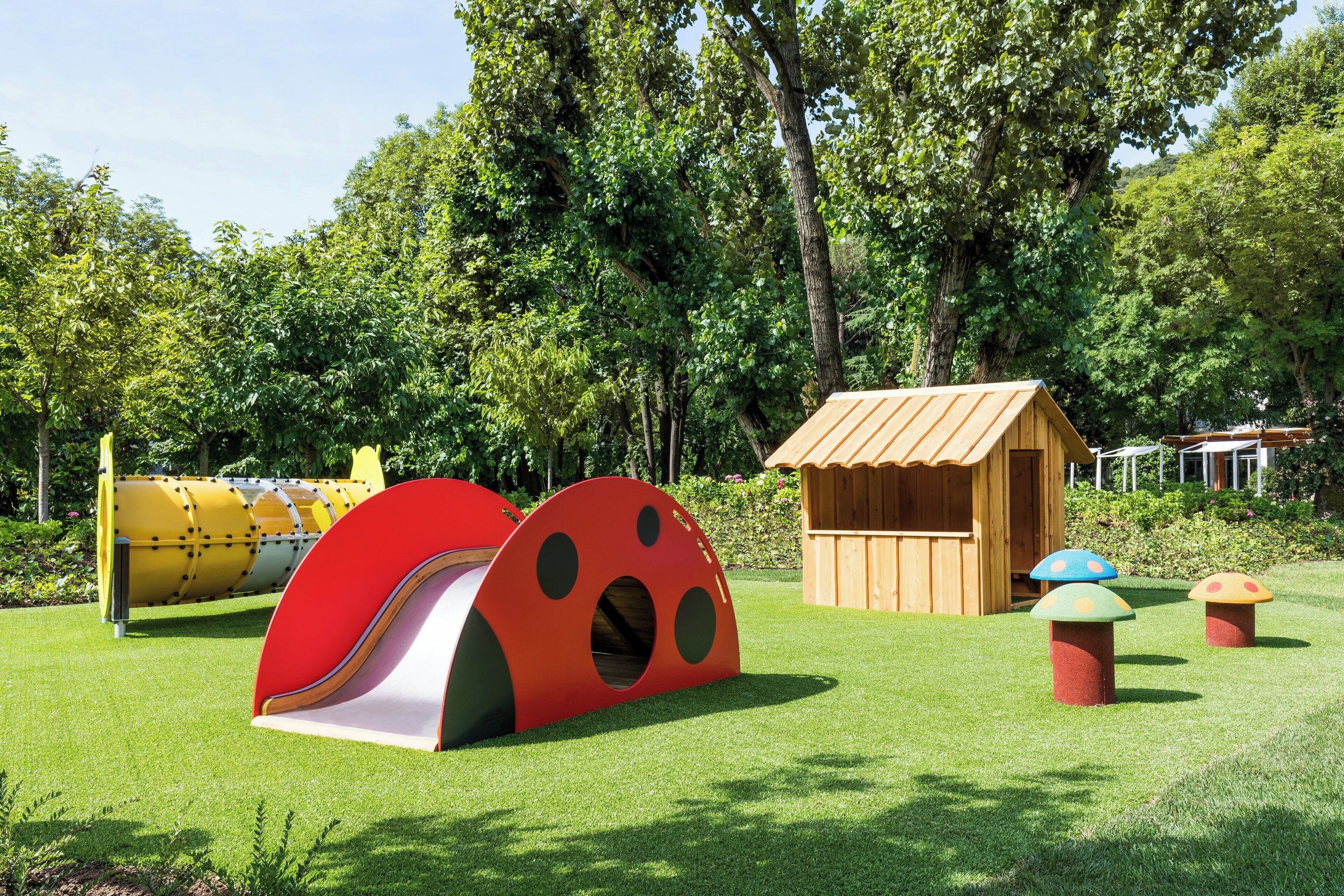 Ein Spielplatz mit Rutsche, Klettergerüst und einer kleinen Holzspielhaus.