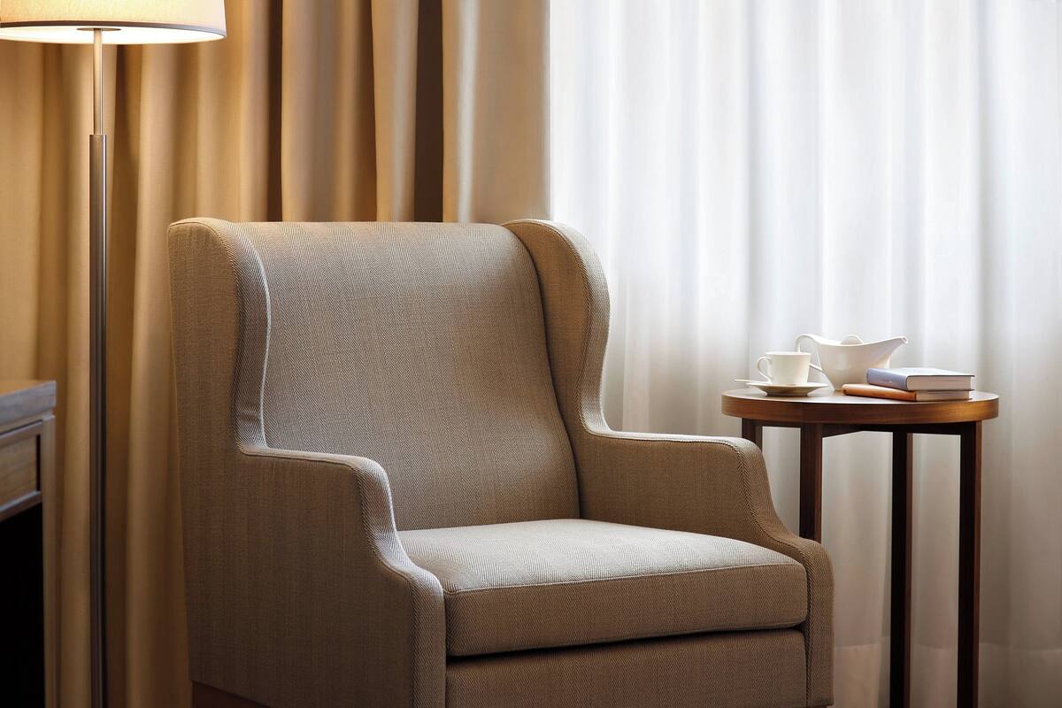 A modern armchair with a textured fabric, positioned next to a small wooden table with a cup and book.