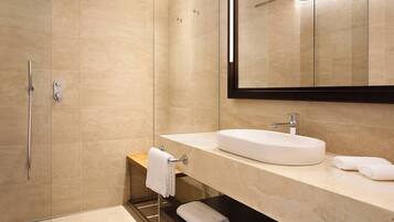Un baño moderno con cabina de ducha de vidrio, un lavabo blanco y un espejo grande.