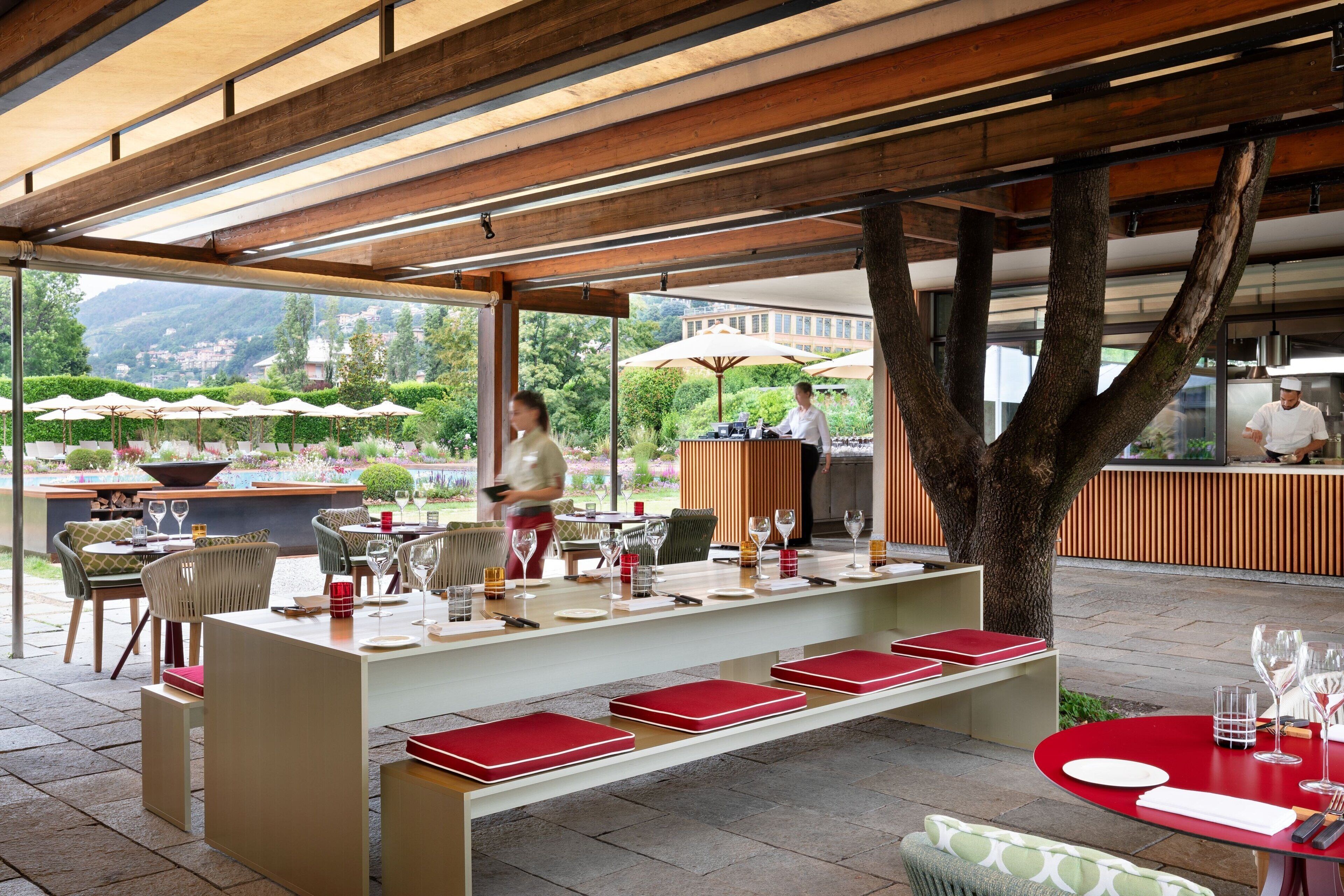 Un'area pranzo all'aperto con travi in legno, un'isola centrale con posti a sedere e vista sul paesaggio circostante.