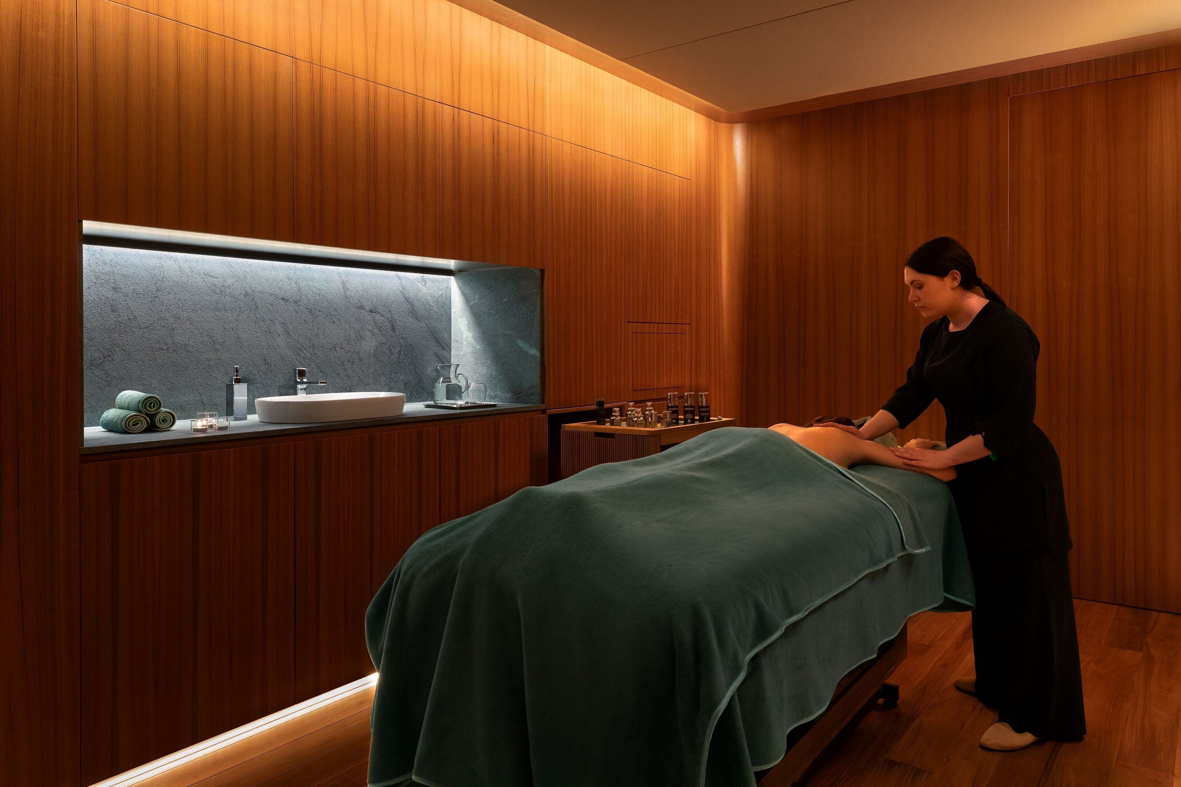 Una stanza per massaggi con parete in legno, un grande specchio e un lettino da massaggio.