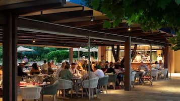 Un'area pranzo all'aperto con diversi tavoli e sedie, riparata da una pergola.