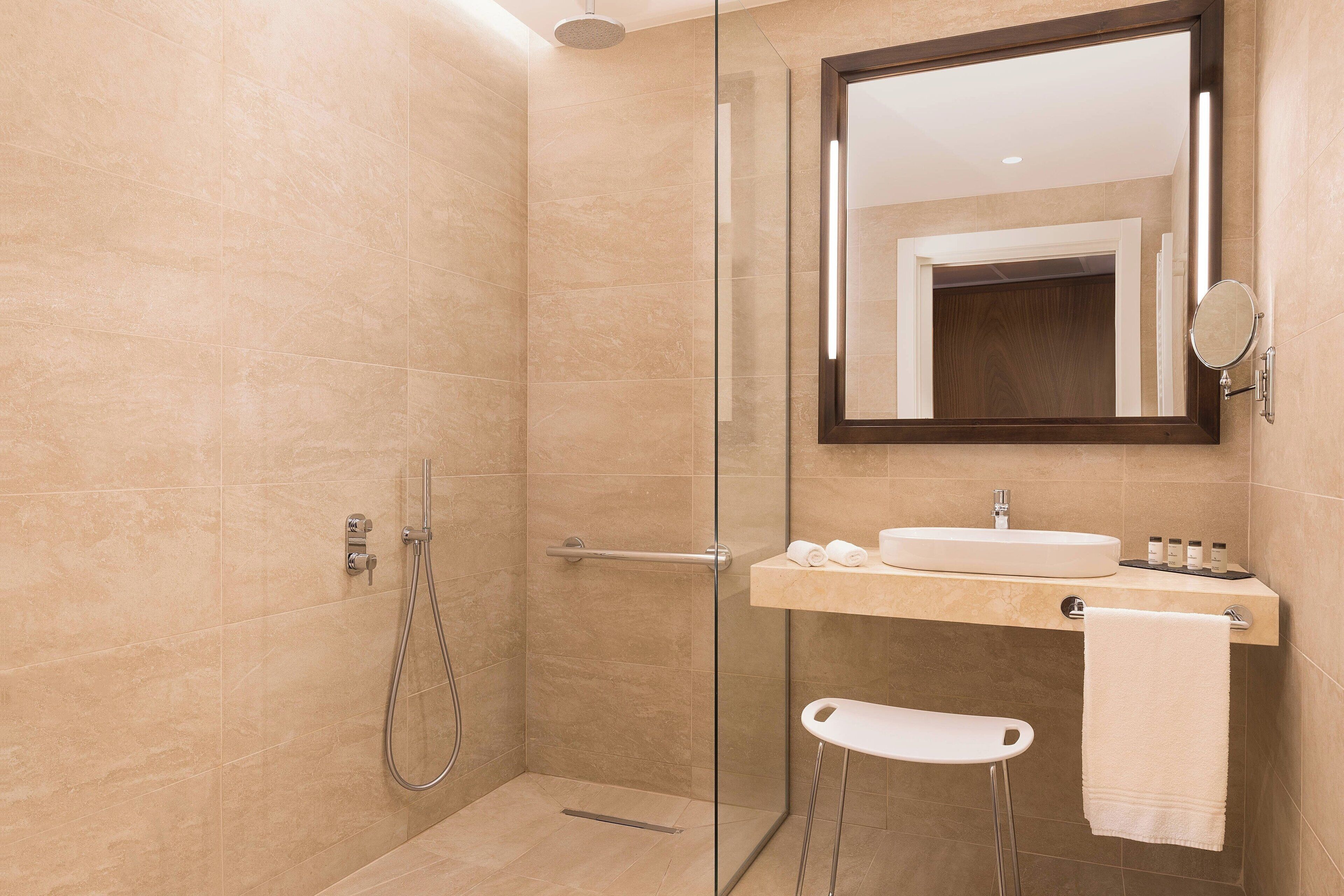 A modern bathroom with a glass shower enclosure, a vanity with a sink, and a mirror.