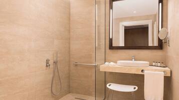 A modern bathroom with a glass shower enclosure, a vanity with a sink, and a mirror.