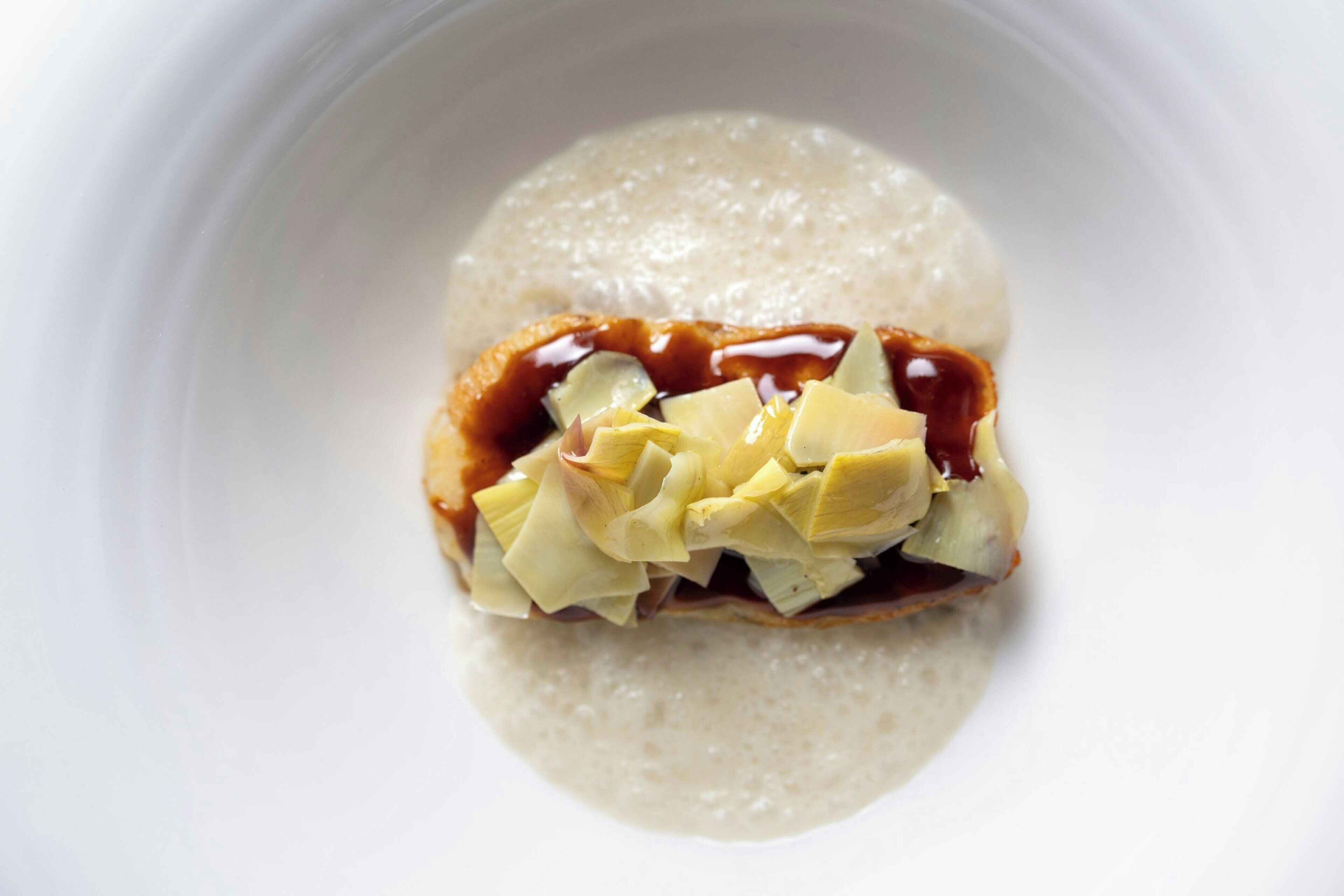 A dessert with a creamy base and a caramelized topping, garnished with a yellow fruit.