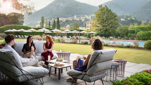 A patio area with outdoor seating, a pool, and a mountainous backdrop. - Sheraton Lake Como Hotel (Como)