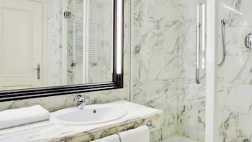 A bathroom with a marble sink, a large mirror, and a glass-enclosed shower.