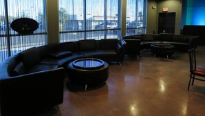 A modern lounge area with a curved sofa, round coffee table, and a flat-screen TV. - Wyndham Garden Midland (Midland)