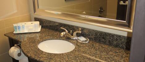 A bathroom with a granite countertop sink, a mirror, and a towel rack.