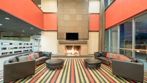 A modern lounge area with a fireplace, striped carpet, and contemporary furniture. - Wyndham Garden Midland (Midland)