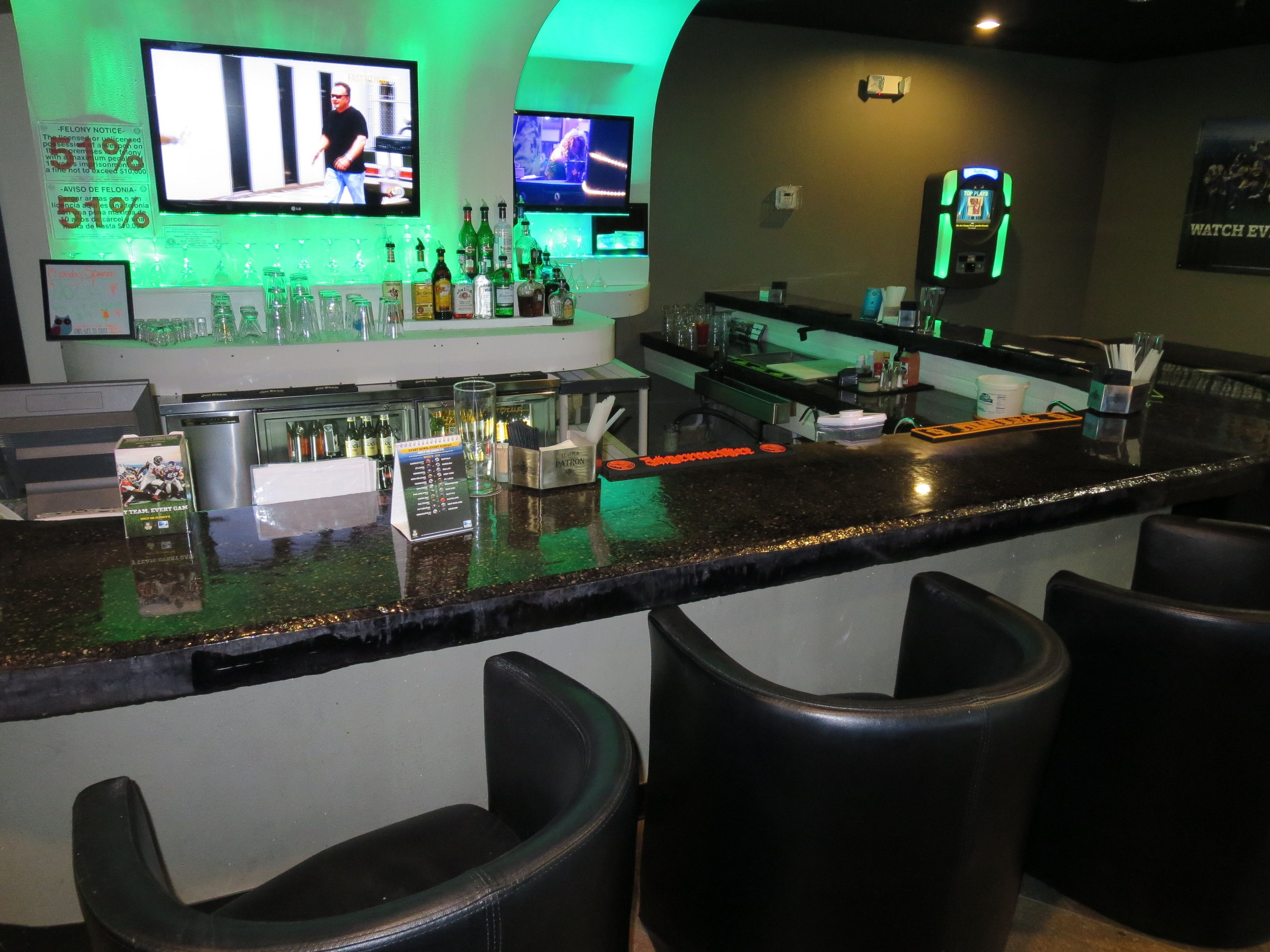 A bar area with a counter, stools, and multiple screens displaying content.