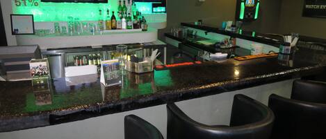 A bar area with a counter, stools, and multiple screens displaying content.